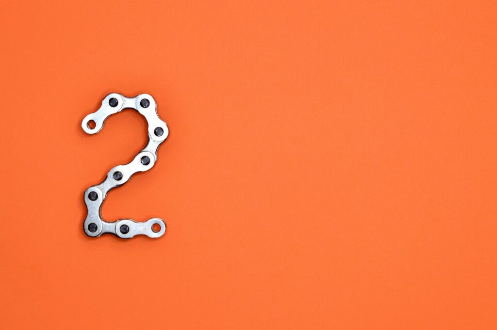 Metal chain forming the number 2 on a bright orange background, perfect for design projects.