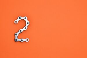 Metal chain forming the number 2 on a bright orange background, perfect for design projects.