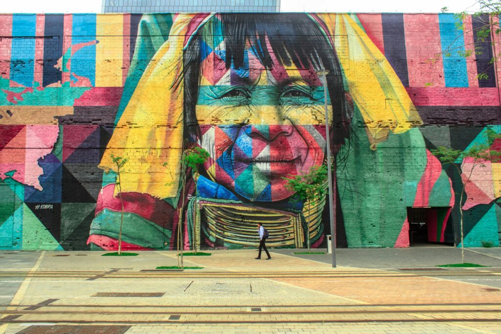 Culture Colorful mural depicting a native face on an urban street wall with a passerby.