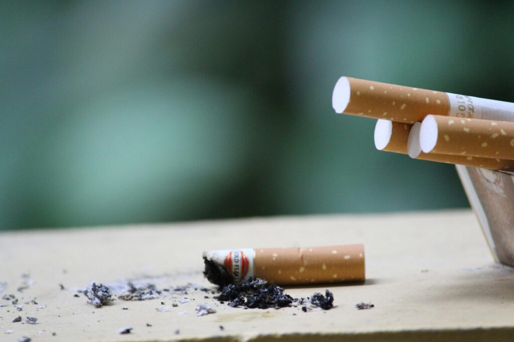 Habits Cigarette with ashes on surface, highlighting tobacco use and health risks.