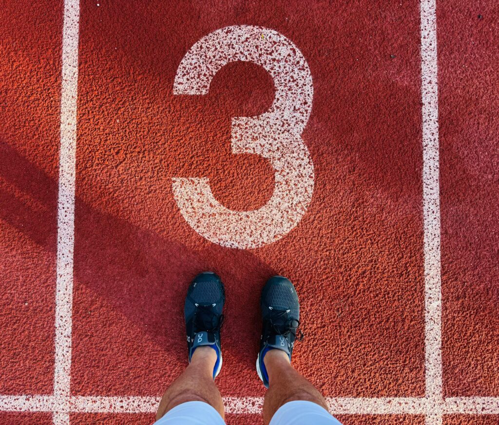 Running shoes on track beside starting block 3, ready to begin race.