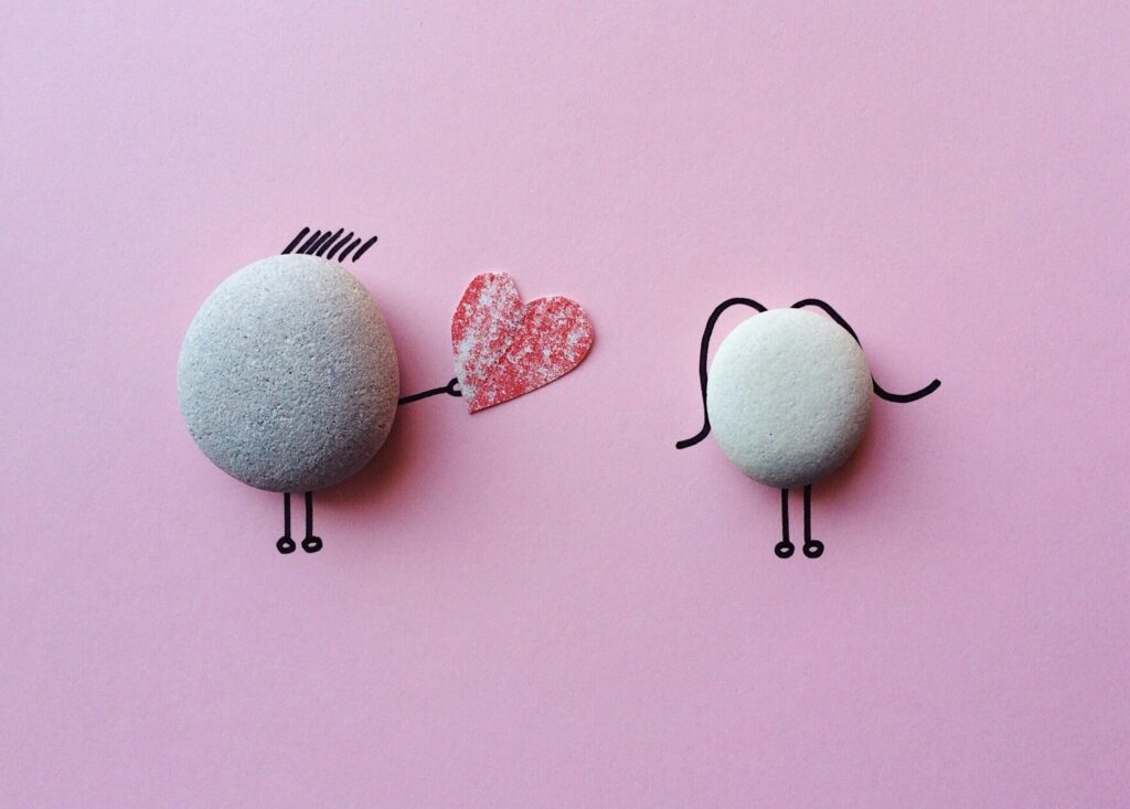 Love Charming stone art with heart symbol on pink background, symbolizing love and connection.