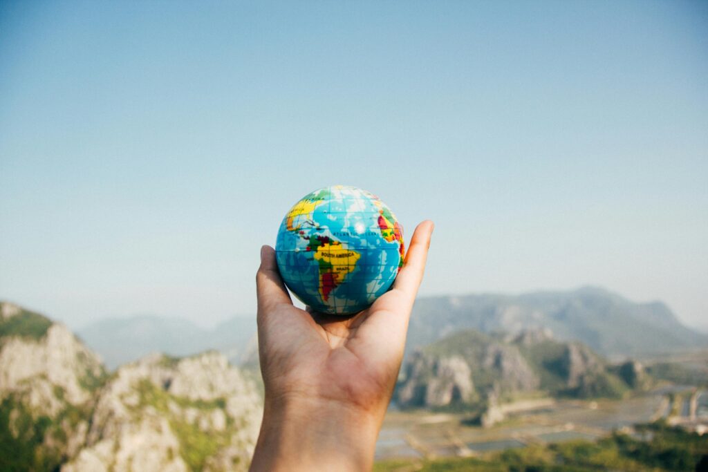 Travel Hand holding a globe against a mountain background symbolizing travel and exploration.
