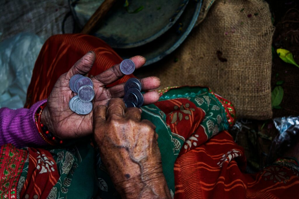 Poverty Close-up of an elderly woman's hands counting coins on a colorful textile background.