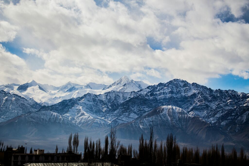 Stunning view of snow-capped mountains under a cloudy sky in Leh, India.